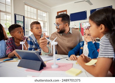 Enthusiastic hispanic teacher explaining to children how wind turbines work with digital tablet. Teacher presenting science project on renewable energy to class in elementary school. - Powered by Shutterstock