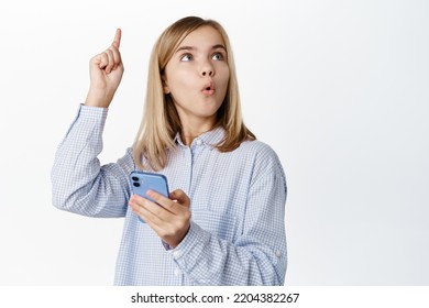 Enthusiastic Little Girl, Child In Casual Clothes, Raising Finger Up, Idea Eureka Gesture, Using Mobile Phone App, Smartphone Application For Kids, Standing Over White Background.