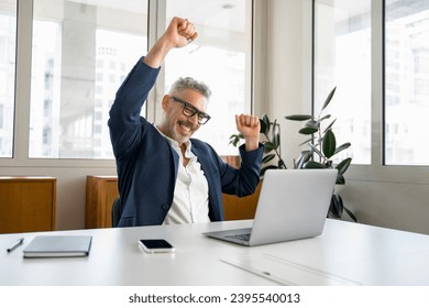 Enthusiastic mature businessman is clenching hands into fists, a happy senior business owner scream yes with triumph, having received great news of good deal, celebrating success of completed project - Shutterstock ID 2395540013