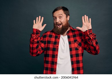 Enthusiastic Modern Guy In Red Checkered Shirt Have Nothing Hide, Raising Hands In Surrender Or Retreatment, Smiling Joyfully, Waving Hands In Hi, Friendly Greeting Gesture, Green-grey Background.