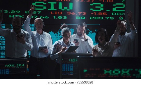 An Enthusiastic Stock Broker Team In A Futuristic Office Full Of Live Global Market Feeds.