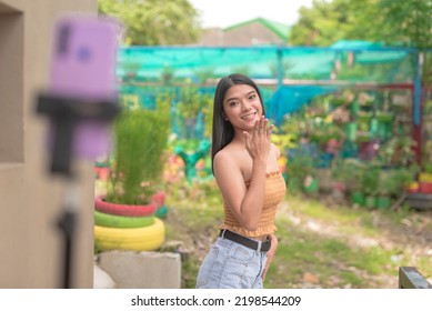 An Enthusiastic Teen Performs While Being Video Recorded By A Phone Mounted On A Tripod As She Tries Most Recent Dance Craze On The Internet.