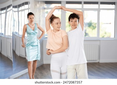 Enthusiastic teenagers, boy and girl in activewear performing elegant waltz in pair in sunny hall of dance school during lesson with female instructor.. - Powered by Shutterstock