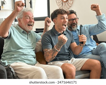 Enthusiastic three generation men family fans watch football championship or olympic games on TV sitting together on sofa, happy grandson with father and old grandfather celebrate team victory - Powered by Shutterstock