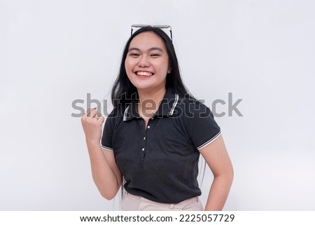 An enthusiastic young asian woman pumps her fist, saying lets do this. A dependable lady full of zeal and eagerness. Isolated on a white backdrop.