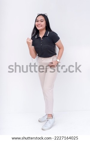 An enthusiastic young asian woman pumps her fist, saying lets do this. A dependable lady full of zeal and enthusiasm. Full body photo isolated on a white backdrop.