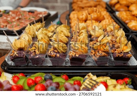 An enticing array of desserts featuring various sweets such as berries, pastries, and physalis-topped treats. perfect for celebrations or gatherings, showcasing a vibrant mix of colors.