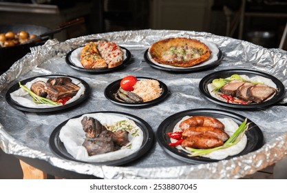 An enticing assortment of grilled meats, fresh vegetables, and fragrant rice is beautifully presented on circular silver trays, capturing the essence of outdoor dining in a lively setting. - Powered by Shutterstock