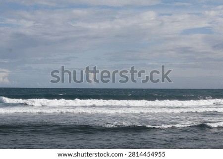 entle ocean waves roll toward the shore beneath a vast sky filled with soft clouds. The peaceful seascape blends deep blue water, white surf, and natural light, creating a calm and refreshing coastal view.