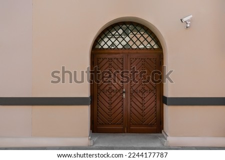 Entrance of building with brown wooden door and CCTV camera