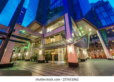 Entrance To The Building Lobby. Night Scene Of Modern Colorful City Life With Skyscrapers, Highrise Buildings. Vancouver Downtown  At Night.