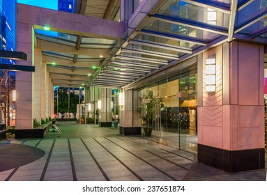 Entrance To The Building Lobby. Night Scene Of Modern Colorful City Life With Skyscrapers, Highrise Buildings. Vancouver Downtown  At Night.