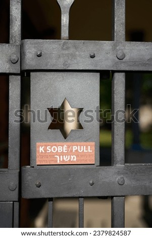  Entrance door to a Jewish cemetery in Prague with Star of David and notice to open the door in three languages                              