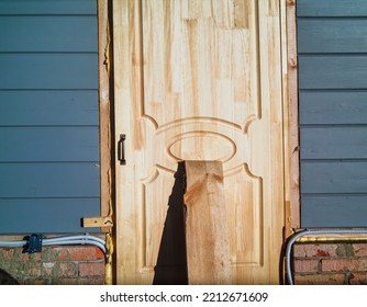 An Entrance Door Loosely Propped By A Board, Concept Of Burglary R Home Invasion 