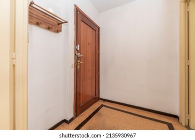 Entrance Door To A Residential House In The Hall With A Wooden Coat Rack Hanging On The Wall