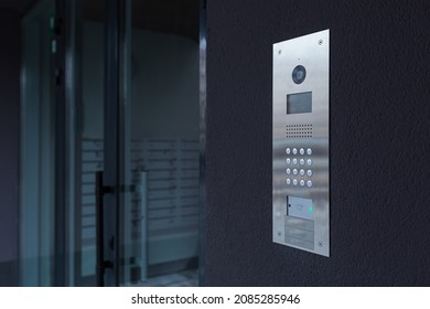 Entrance doorbell in a multi-apartment building, with a video surveillance camera, on a dark wall - Shutterstock ID 2085285946