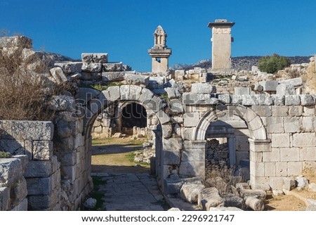 Entrance gate to theatre of Xanthos ancient city - part of Lycian way. Tomb monument of king Kybernis ( Harpy Tomb), Pillar Tomb on background. Popular travel destination in Antalya, Turkey