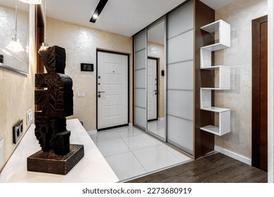 Entrance hall in the apartment with a large wardrobe with a mirror, soft pouf and other furniture. - Shutterstock ID 2273680919