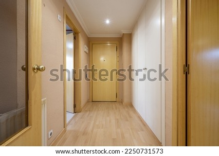 Entrance hall with armored door of an empty house with white built-in cabinets and light wooden doors