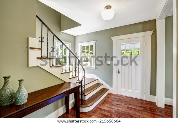 Entrance hallway with staircase and table. View\
of steps with wrought iron\
railings