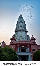 The entrance of the Hindu temple New Vishwanath Mandir inside the Banaras Hindu University campus against the backdrop of blue sky with flying pigeons. - Shutterstock ID 526062895