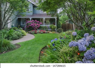 Entrance to a home through a beautiful garden, highlighted by rose and blue hydrangeas.