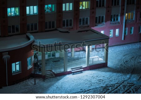 Entrance to the hospital overnight. Veranda clinic in the winter. People on the porch under the lantern. Building's facade.