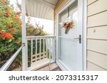 Entrance of a house with glass storm door over the white door with hanging flower decoration