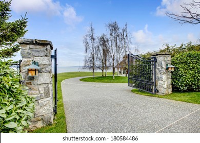 Entrance Iron Gates With Stone Columns. View Of Driveway And Roundabout.