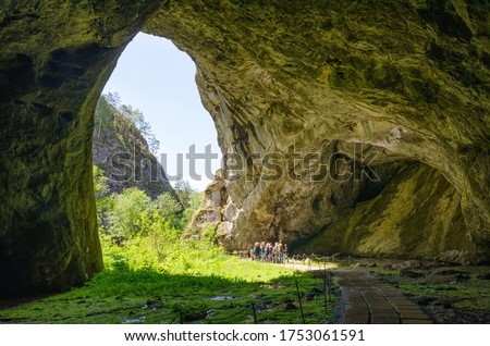 Entrance of Kapova Cave (Shulgan-Tash cave) with group of tourists in it. Bashkiria national park, Bashkortostan, Russia.