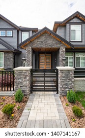 Entrance Of Luxury Residential House With Metal Gate And Stone Textured Walls. Big Family House Entrance With Landscaped Front Yard