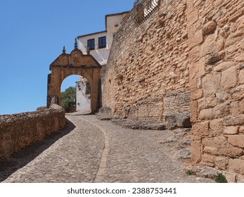 Entrance to the old Ronda city. Stone masonry monumental arch 'Arco de Felipe V' or 'Arab Gate' and street from the bridge Puente Viejo which span the deep El Tajo canyon that carries Guadalevín River