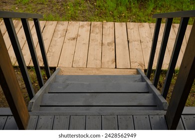 Entrance staircase of a traditional wooden house. Detail of a wooden porch - steps and railings. Concept of a country house, rural life. - Powered by Shutterstock