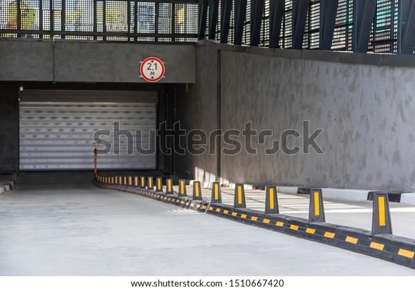 Entrance to underground car park with\
roller-shutter door and road\
dividers