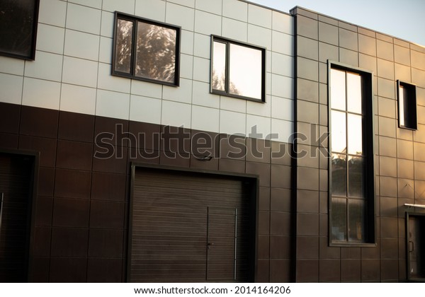 Entrance to the\
underground garage. The gate to the garage in the building. The\
office building is brown. A modern facing panel for a technical\
structure. Windows in a private\
office.