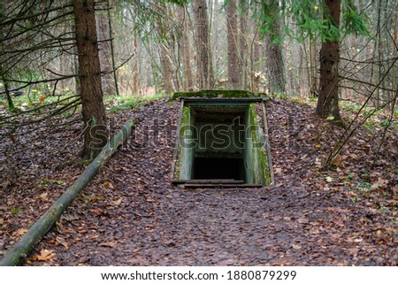 Entrance to underground military bunker in the forest. Former concrete dugout in woodland used during the war