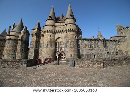 entrance of Vitre castle and Vitre town hall with drawbridge, walls and pointed towers at sunny day with blue sky 