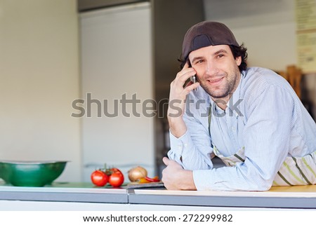 Entrepeneur smiling while making a call on his phone from his takeaway food business 