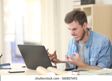 Entrepreneur angry and furious with a laptop in a little office or home
