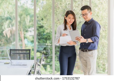 Entrepreneur Asian Businessman And Woman Discussing New Business Project In Tablet In Modern Meeting Room