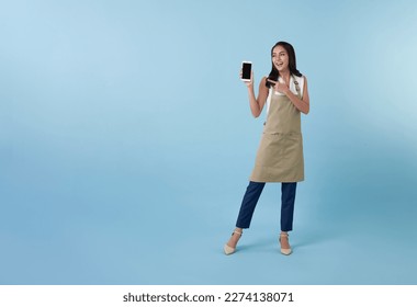 Entrepreneur asian woman showing and hand pointing finger to blank screen smartphone on blue studio background. full length  - Powered by Shutterstock