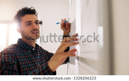 Entrepreneur discussing business ideas and plans on a board. Businessman writing on whiteboard using a marker pen.