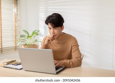 Entrepreneur Handsome Business Asian Man Wear Casual Shirt Working Online On Desk Table Smile And Happiness With Laptop At Home.Attractive Freelance Man Working Online Sale Marketing At Home Office