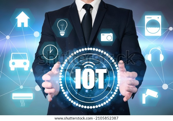 An entrepreneur holds up the symbol\
for IOT, Internet of Things. Connectivity via the internet of a\
smart home, watch, car and home appliances.\
Domotics