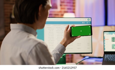 Entrepreneur Looking At Horizontal Greenscreen On Smartphone, Using Blank Chroma Key With Mockup Copyspace Template And Isolated Background. Mobile Phone Application On Display.