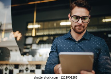 Entrepreneur Looking At A Tablet Computer Sitting At A Restaurant. Businessman Managing Business Sitting At A Restaurant.