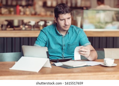 Entrepreneur managing his small business - Businessman looking overwhelmed - Young coffee shop owner going through paperwork