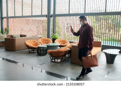 Entrepreneur In Medical Mask And Earbuds Video Calling Business Partner When Coming To Office Building