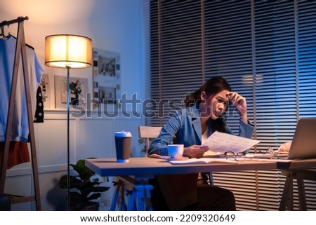 Entrepreneur using tablet pc while working from dark office working on deadline. Business asian woman working overtime at home.