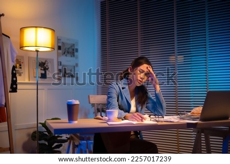 Entrepreneur using tablet pc while working from dark office working on deadline. Business asian woman working overtime at home.
